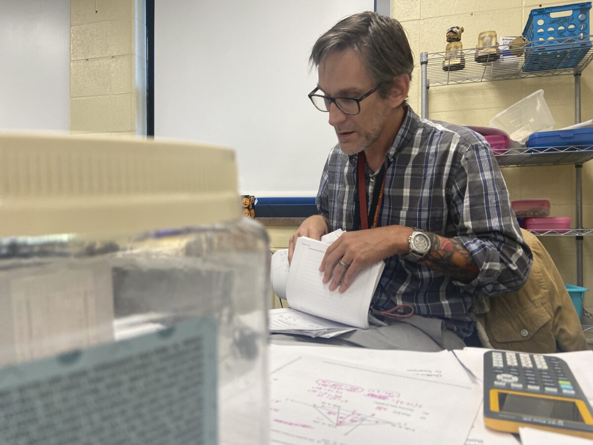 Mr. Shiner, a new Atherton math teacher, sorts through worksheets at his desk after school. 