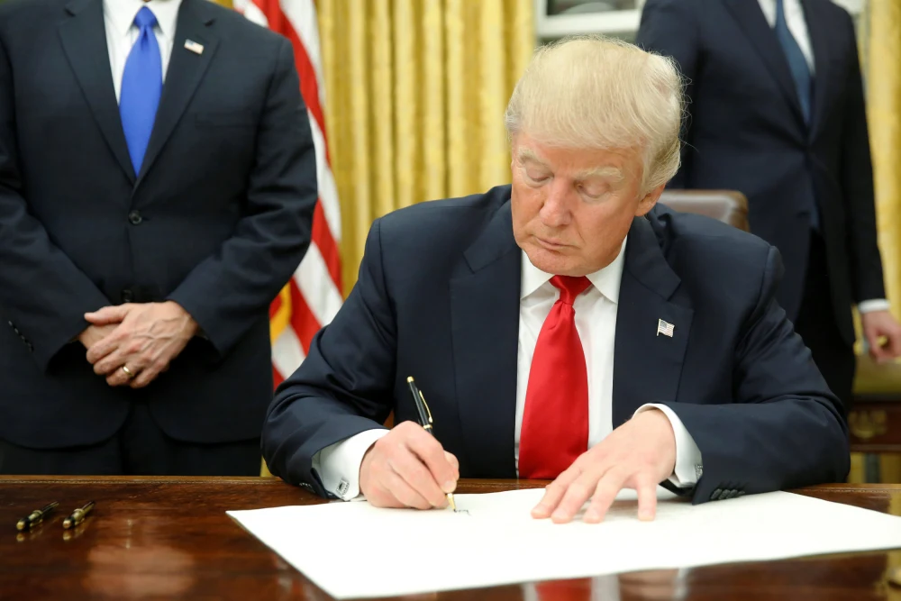 President Donald Trump signs his first executive orders in the Oval Office in Washington, D.C. on Jan. 20.