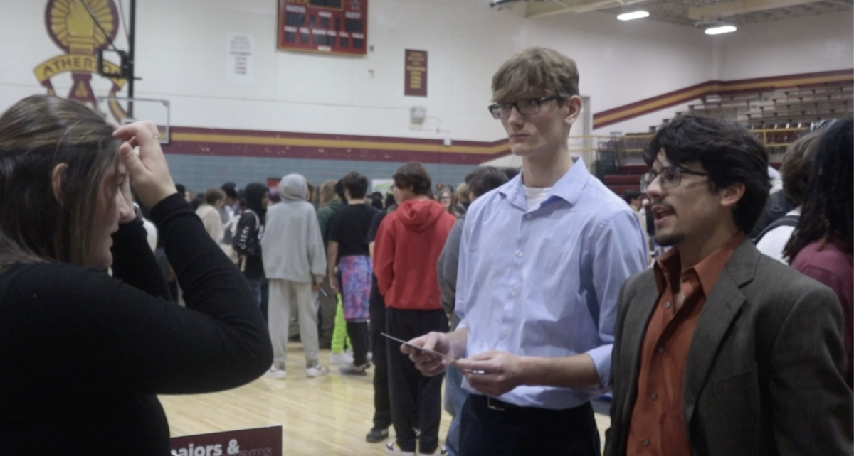 Andrew Sims (12, center) and Trey Leister jr. (12, right) talk with an admissions counselor at the college fair