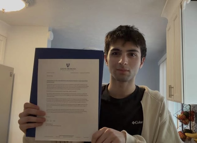 Azam Tashtanov (12) poses with his Johns Hopkins acceptance letter.